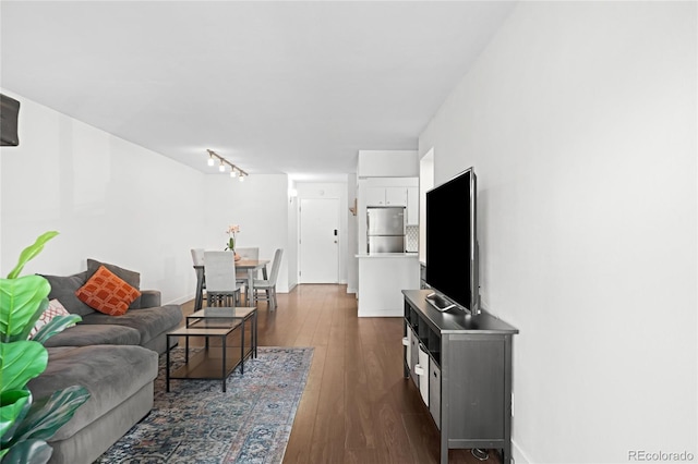 living area with dark wood-style floors, rail lighting, and baseboards