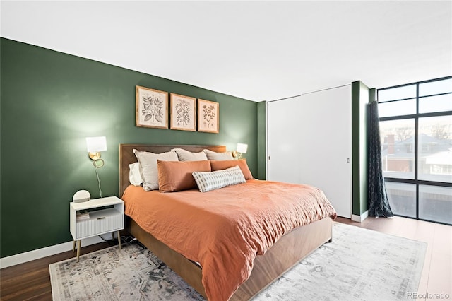 bedroom with baseboards, wood finished floors, and floor to ceiling windows