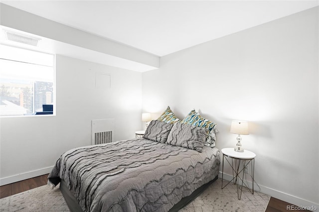 bedroom featuring visible vents, baseboards, and wood finished floors