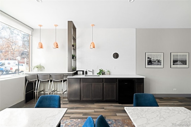 bar featuring baseboards, pendant lighting, a sink, and wood finished floors