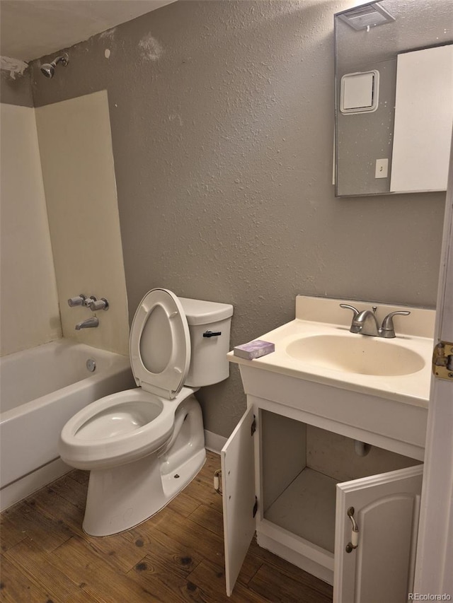 16094 E Exposition Dr, Aurora, CO 80017 - bathroom with wood finished floors, vanity, toilet, a textured wall, and bathtub / shower combination