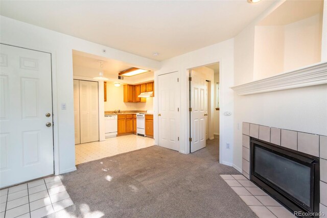 unfurnished living room with a tiled fireplace and light tile patterned flooring