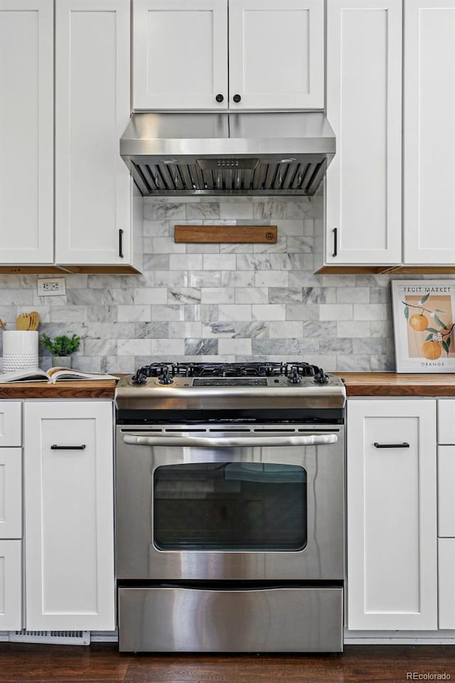 kitchen with stainless steel gas range, butcher block countertops, extractor fan, white cabinetry, and decorative backsplash