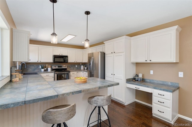 12814 Forest Cir, Thornton, CO 80241 - kitchen with stainless steel appliances, a sink, a peninsula, dark wood-type flooring, and a breakfast bar