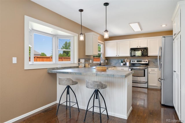 12814 Forest Cir, Thornton, CO 80241 - kitchen with appliances with stainless steel finishes, a peninsula, dark wood finished floors, white cabinetry, and recessed lighting