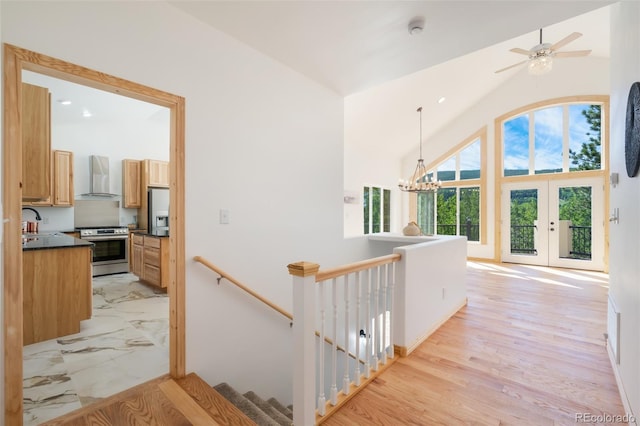 corridor with an inviting chandelier, light hardwood / wood-style floors, high vaulted ceiling, and sink