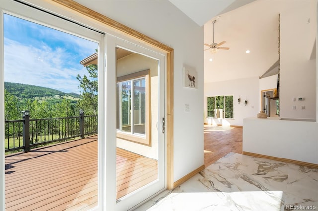 doorway to outside featuring ceiling fan, light wood-type flooring, and vaulted ceiling