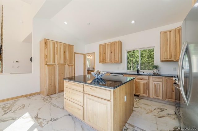 kitchen featuring light brown cabinets, stainless steel appliances, vaulted ceiling, and a center island