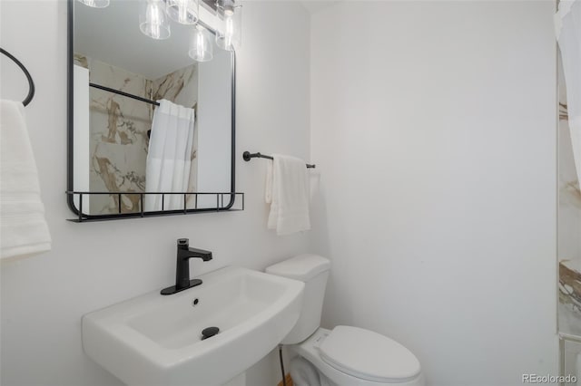 bathroom featuring a shower with shower curtain, toilet, and sink