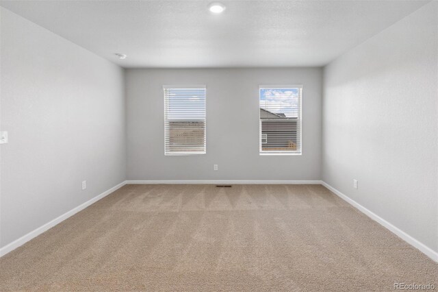 empty room with a textured ceiling, carpet flooring, visible vents, and baseboards