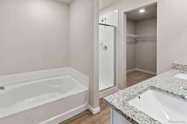 bathroom with hardwood / wood-style flooring, double vanity, and plus walk in shower