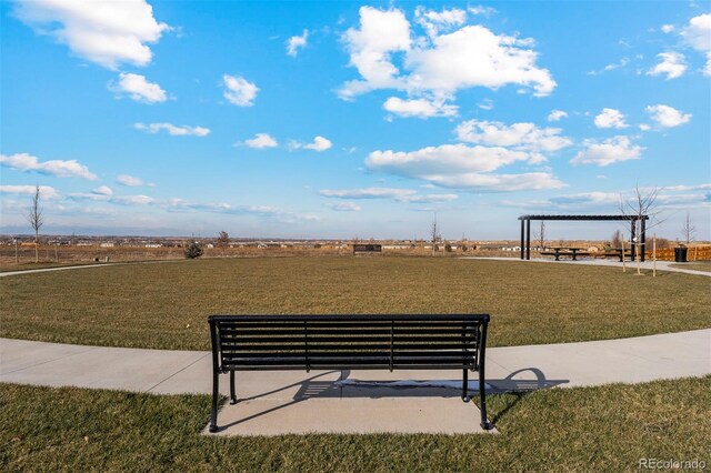 view of property's community with a rural view, a yard, and a pergola