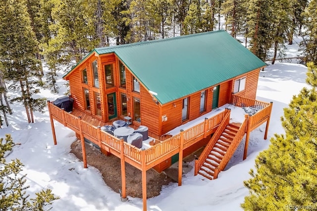 snow covered back of property featuring metal roof, a deck, and stairs