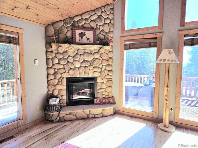 unfurnished living room featuring visible vents, lofted ceiling, wooden ceiling, wood finished floors, and a fireplace