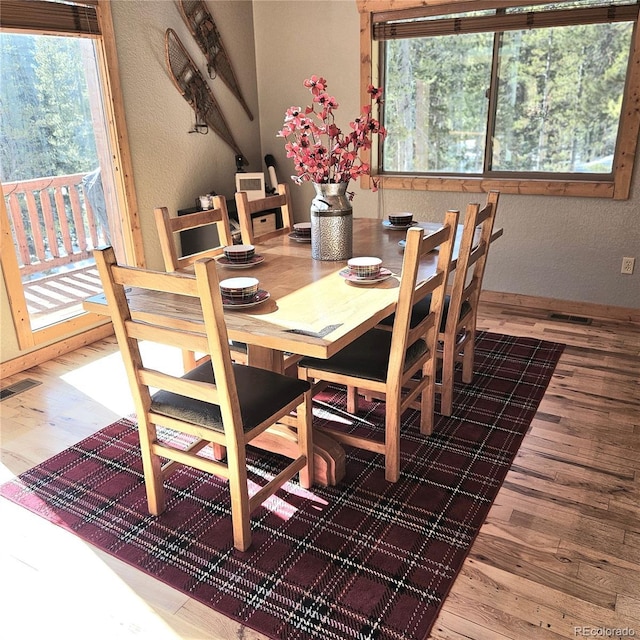 dining room with a textured wall, plenty of natural light, wood finished floors, and visible vents