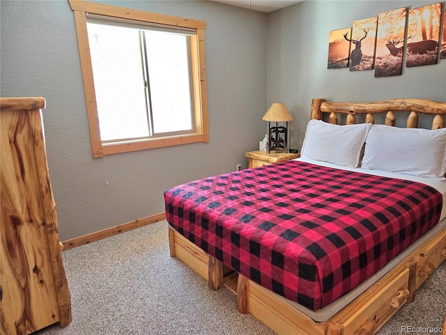 carpeted bedroom with a textured wall and baseboards