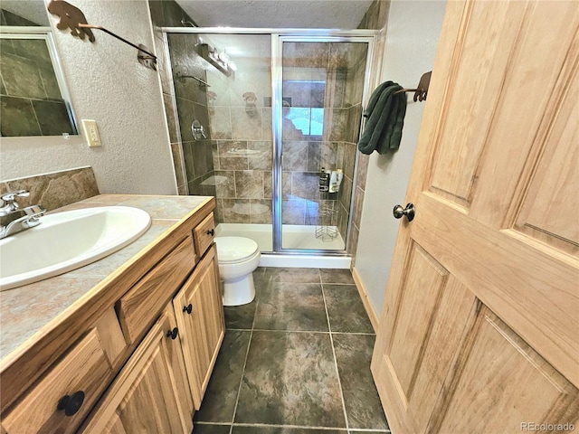 full bath with a textured wall, toilet, a textured ceiling, a shower stall, and vanity