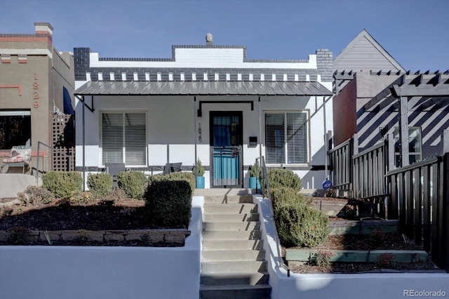 view of front of property with stucco siding, a porch, and metal roof