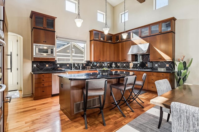 kitchen featuring glass insert cabinets, dark countertops, a center island, and appliances with stainless steel finishes