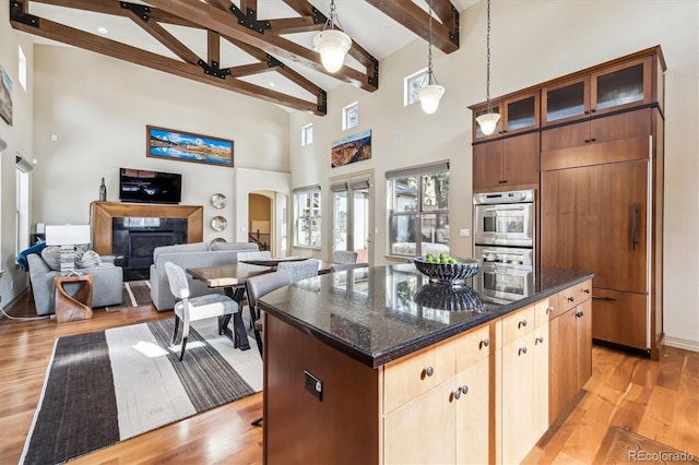 kitchen with a center island, arched walkways, paneled built in fridge, glass insert cabinets, and open floor plan