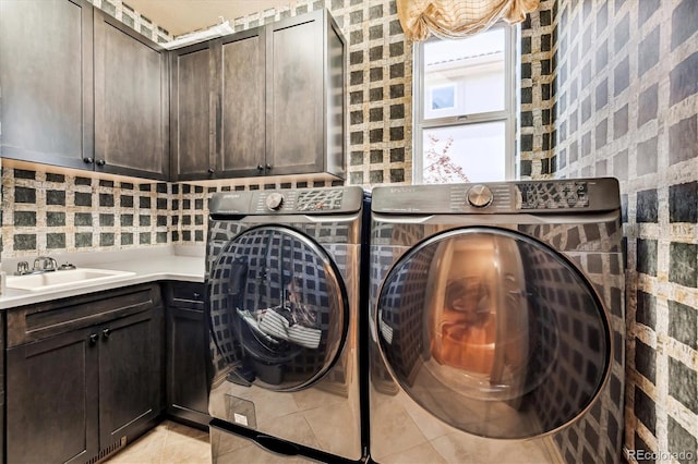 laundry room with light tile patterned flooring, independent washer and dryer, a sink, and cabinet space