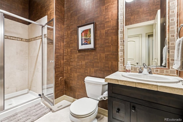 bathroom with a stall shower, vanity, toilet, and tile walls