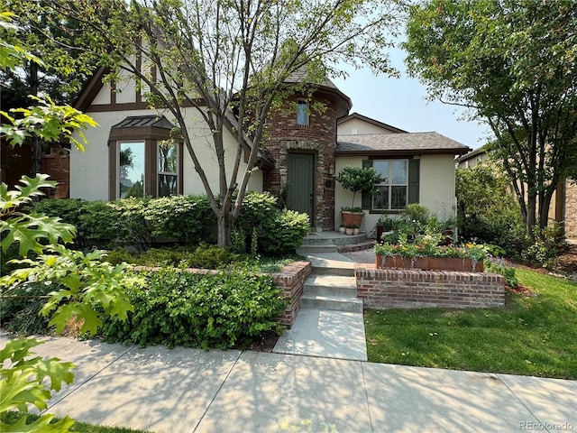 tudor house featuring roof with shingles and stucco siding