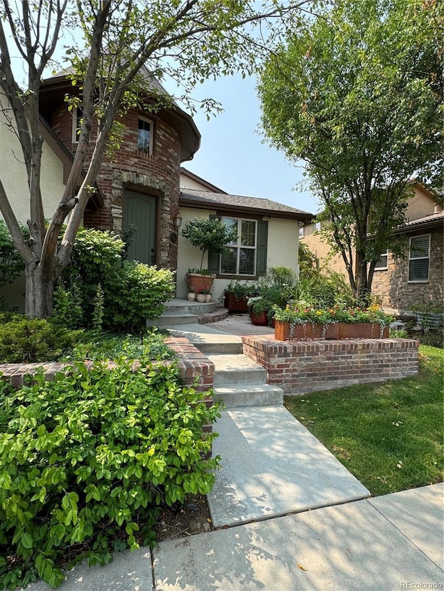 view of front of property featuring brick siding and stucco siding