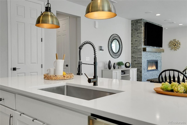 4040 Eaton Park St, Aurora, CO 80019 - kitchen with a sink, light countertops, pendant lighting, white cabinetry, and a fireplace