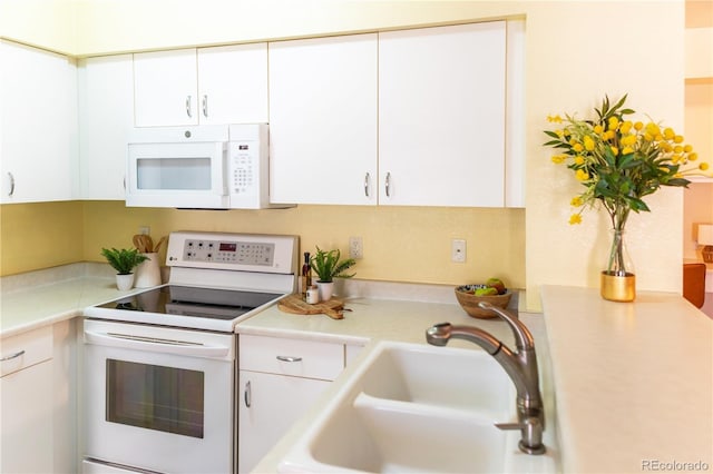 kitchen with sink, white appliances, and white cabinetry