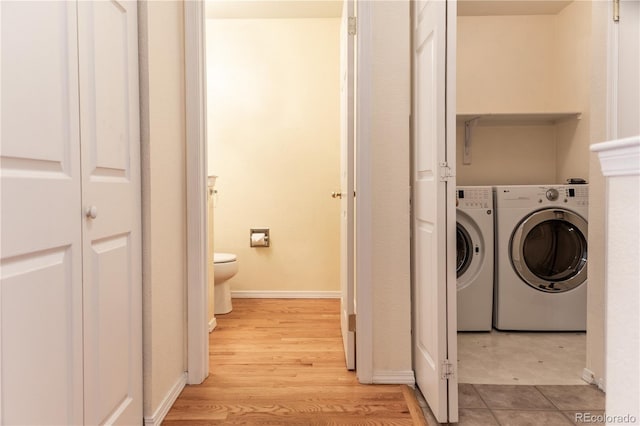 washroom with washer and clothes dryer and light hardwood / wood-style flooring