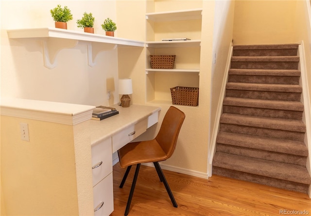 home office featuring light hardwood / wood-style floors and built in desk