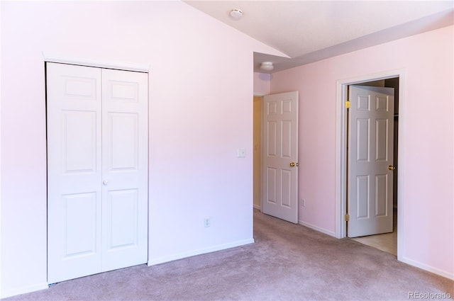 unfurnished bedroom with light colored carpet, a closet, and vaulted ceiling