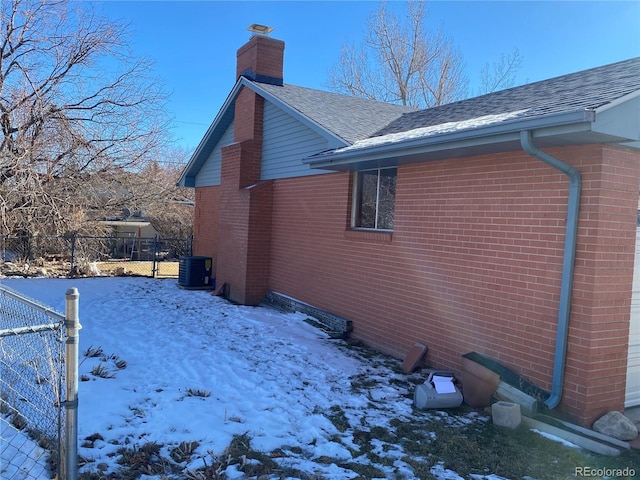 snow covered property with central AC