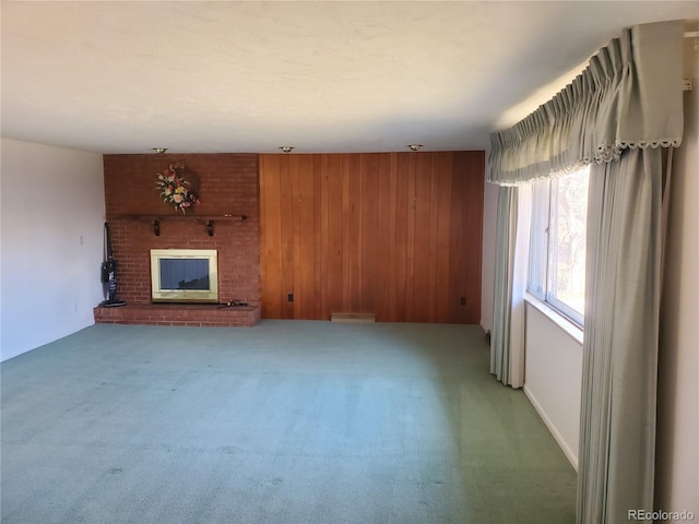 unfurnished living room featuring a fireplace, wooden walls, and carpet