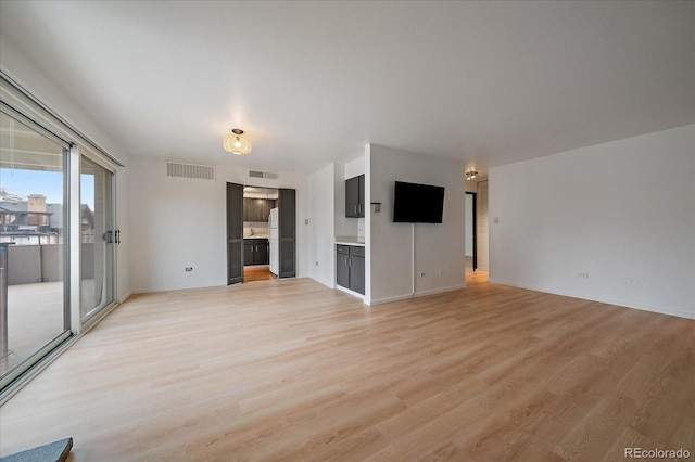 unfurnished living room featuring light wood-style floors, baseboards, and visible vents