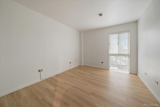 spare room featuring visible vents, light wood-style flooring, and baseboards