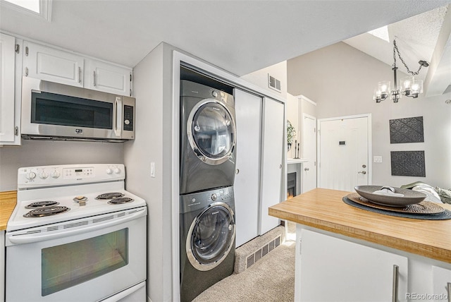 kitchen with decorative light fixtures, stacked washer / dryer, a chandelier, white electric range, and white cabinetry