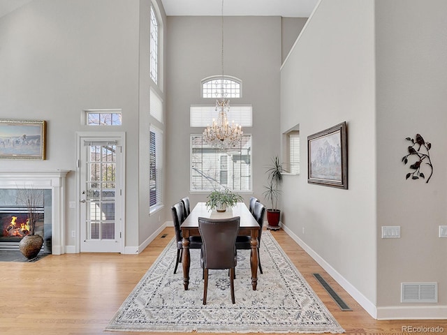 8312 S Peninsula Dr, Littleton, CO 80120 - dining room featuring a chandelier, light wood-type flooring, a high ceiling, and healthy amount of natural light
