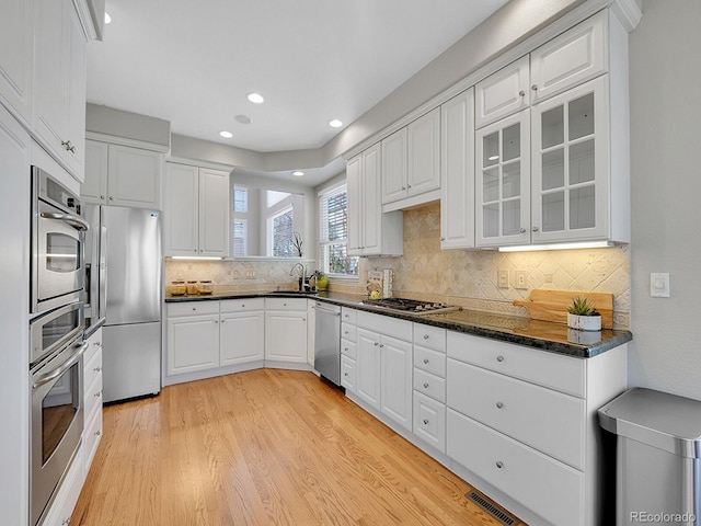 8312 S Peninsula Dr, Littleton, CO 80120 - kitchen featuring stainless steel appliances, white cabinetry, light wood-style flooring, backsplash, and glass insert cabinets