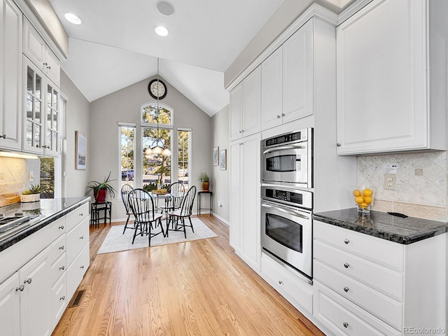 8312 S Peninsula Dr, Littleton, CO 80120 - kitchen with double oven, white cabinetry, lofted ceiling, light wood-style floors, and backsplash