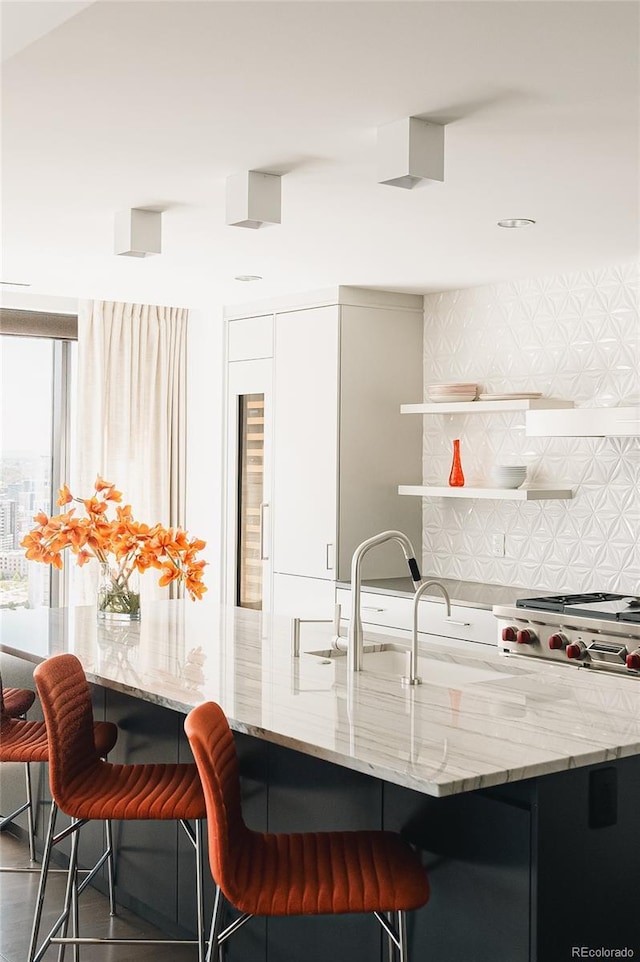 kitchen featuring tasteful backsplash, light stone countertops, and a kitchen breakfast bar