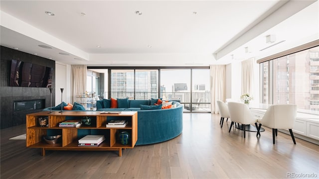 living room featuring expansive windows, light wood-type flooring, and a large fireplace