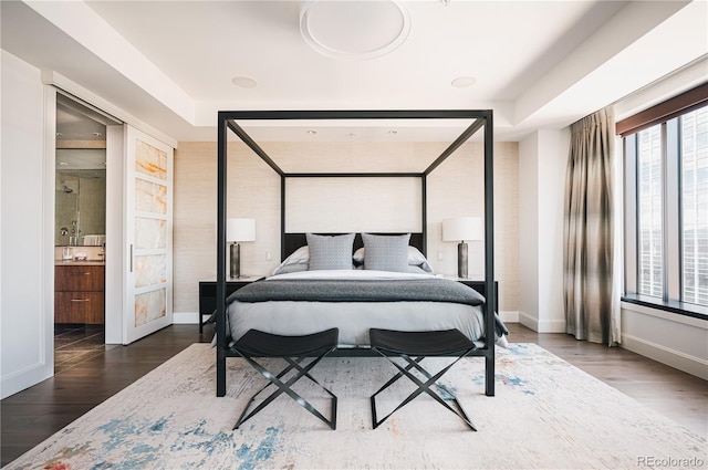 bedroom with ensuite bathroom and dark wood-type flooring