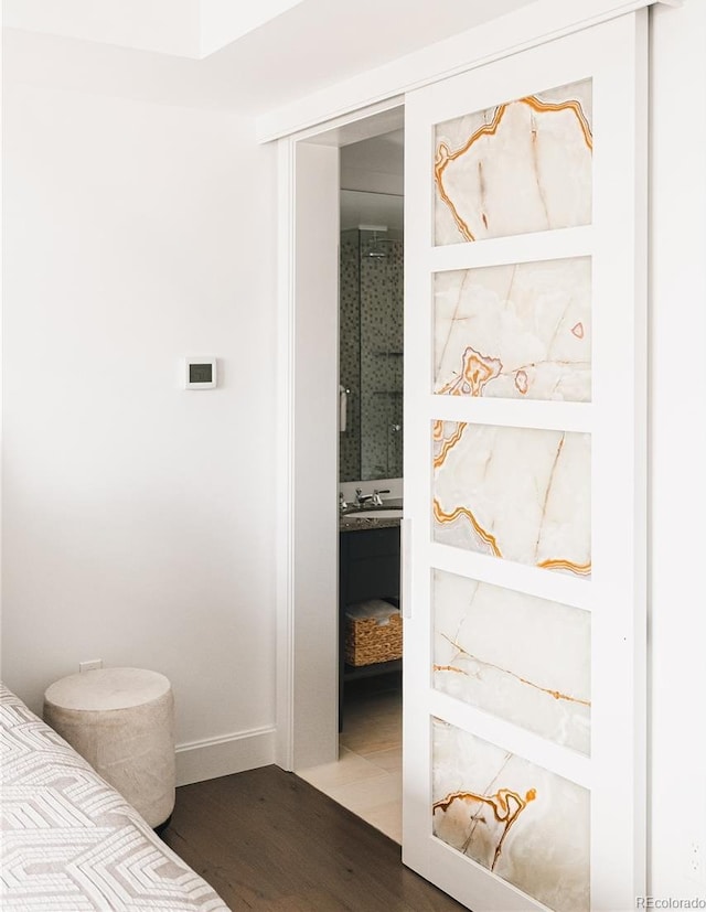 bedroom with ensuite bathroom and wood-type flooring