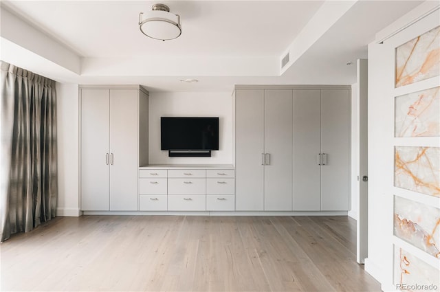 unfurnished bedroom featuring a tray ceiling and light hardwood / wood-style floors