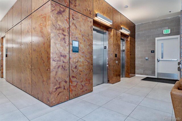 hall featuring light tile patterned flooring and elevator