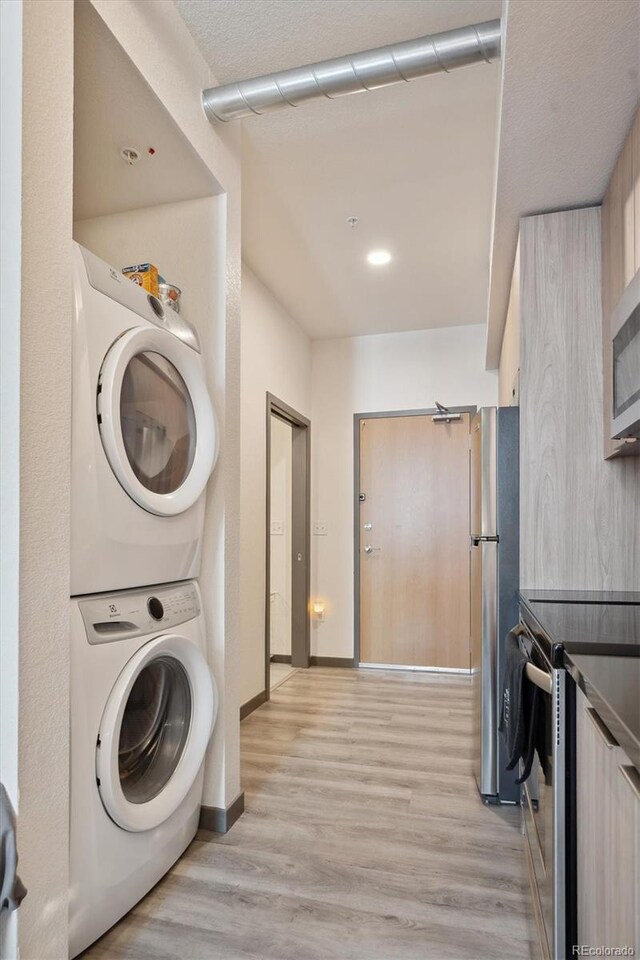 laundry room featuring light hardwood / wood-style floors and stacked washing maching and dryer