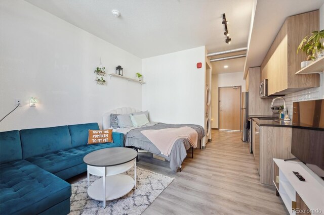 bedroom featuring track lighting, light hardwood / wood-style flooring, and stainless steel fridge