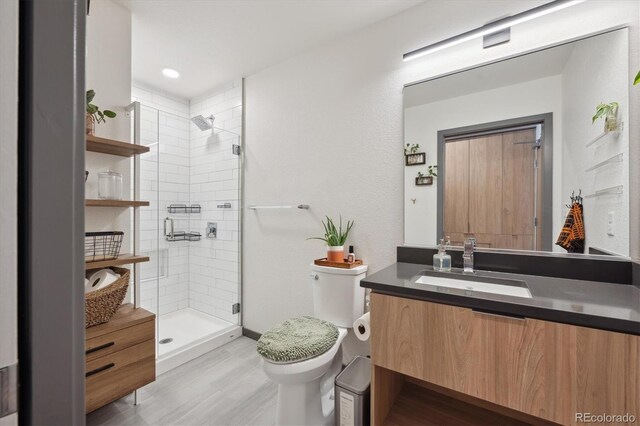 bathroom featuring toilet, hardwood / wood-style floors, walk in shower, and vanity